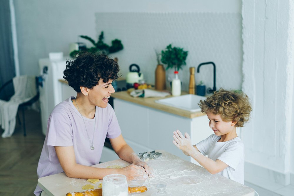 Foster parent and child baking at kitchen table